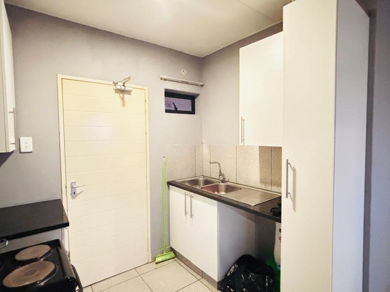 Compact kitchen area featuring built-in cabinetry, a stainless steel sink, and a black countertop, providing a functional space for meal preparation.