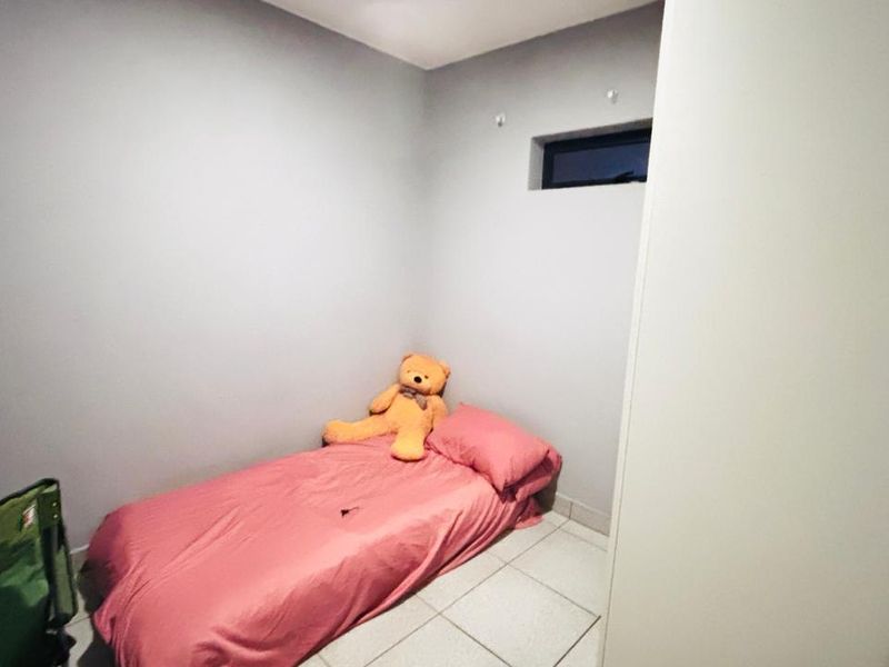 A compact bedroom featuring tiled flooring and a high-set horizontal window, providing a simple and functional living space.
