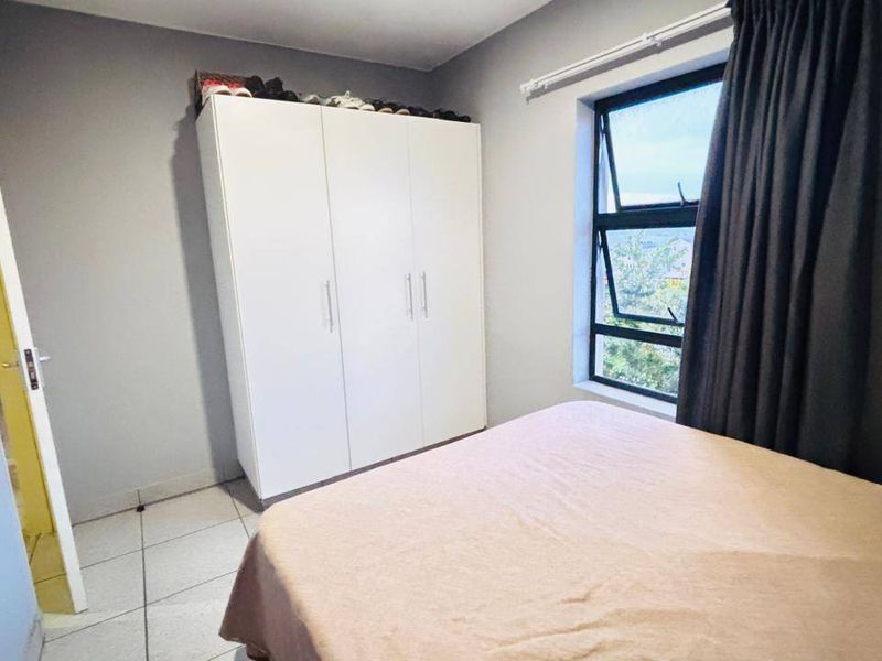 A bedroom featuring tiled flooring, a built-in wardrobe, and a window with natural light.