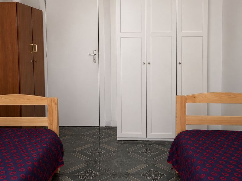 A bedroom featuring built-in white cabinetry and patterned tiled flooring.