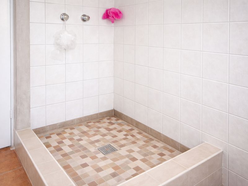 A clean, walk-in shower enclosure featuring neutral-toned wall and floor tiling, ready for modern updates or fixtures.