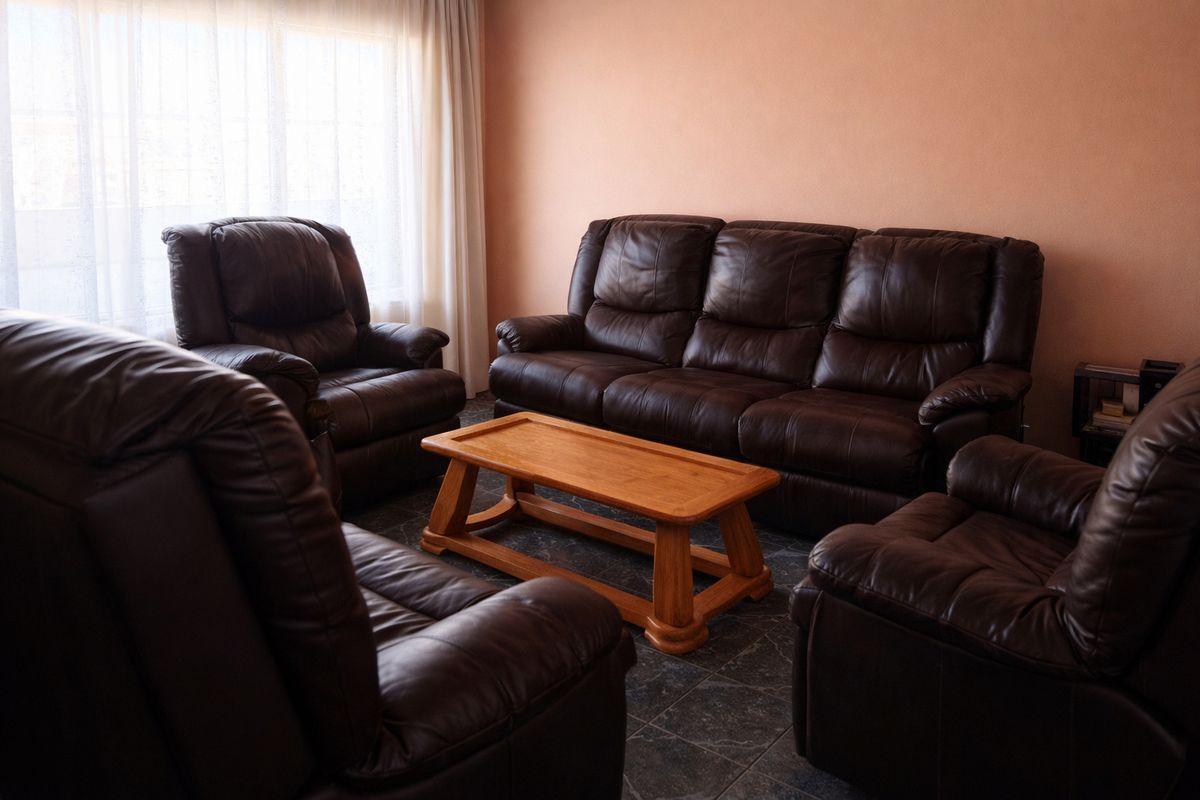 A living room featuring tiled flooring and natural light through window curtains.