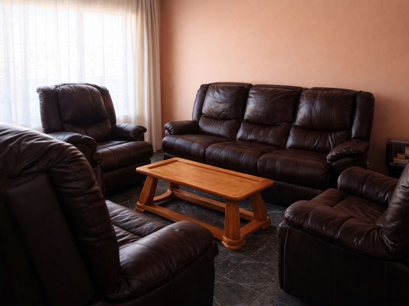 A living room featuring tiled flooring and natural light through window curtains.