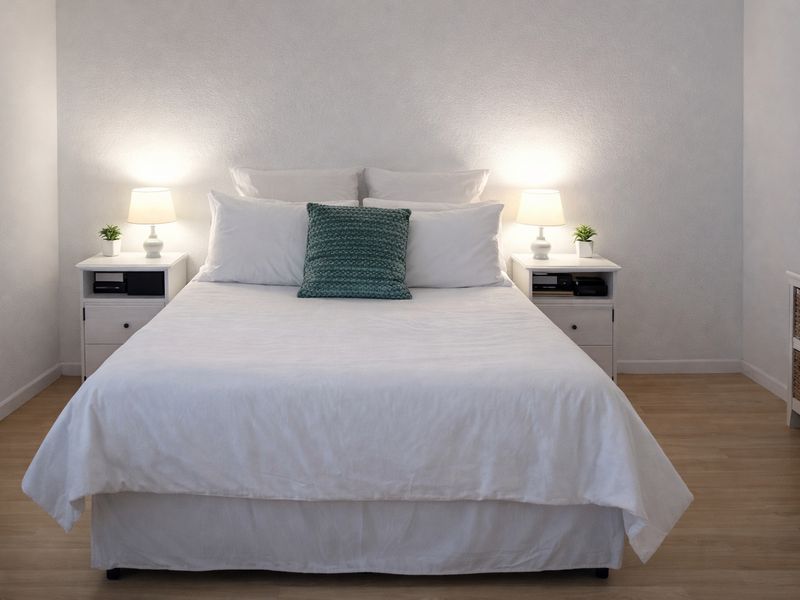 A well-lit bedroom featuring light-toned laminate flooring and a neutral color palette, creating a clean and inviting atmosphere.