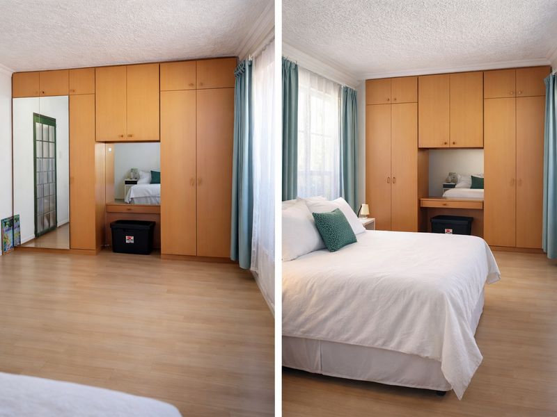A bedroom featuring light laminate flooring and extensive built-in wooden cabinetry with an integrated vanity and mirrored wardrobe doors.