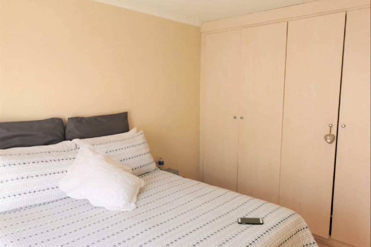 A bedroom featuring neutral wall tones and a functional built-in wardrobe with ample storage space.