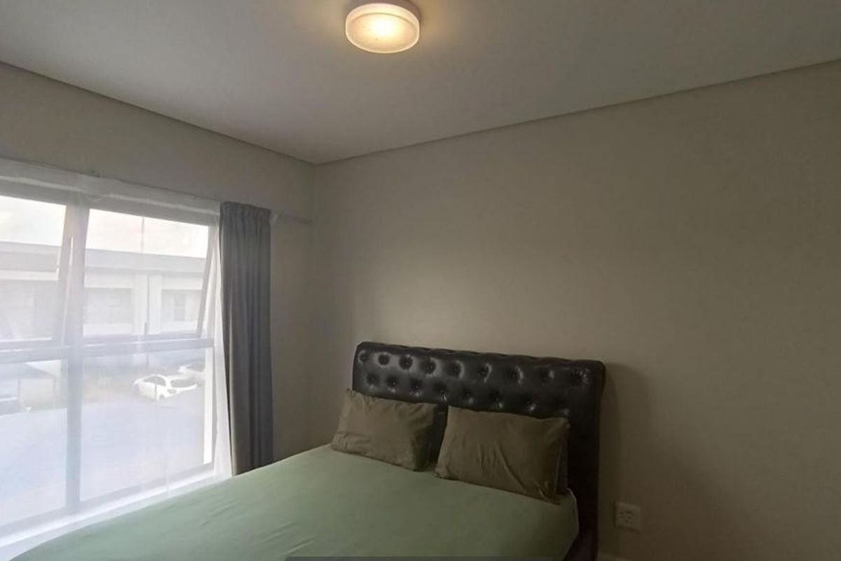 A functional bedroom featuring a window with curtains and a central ceiling light fixture, providing a neutral space for rest.