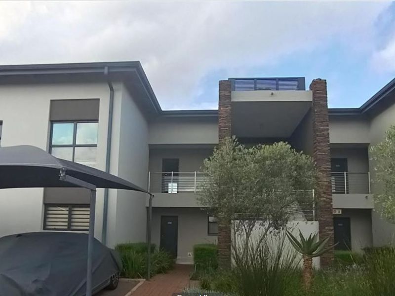 Front elevation of a modern apartment complex featuring stone cladding accents, private balconies with stainless steel balustrades, and covered parking shade ports.