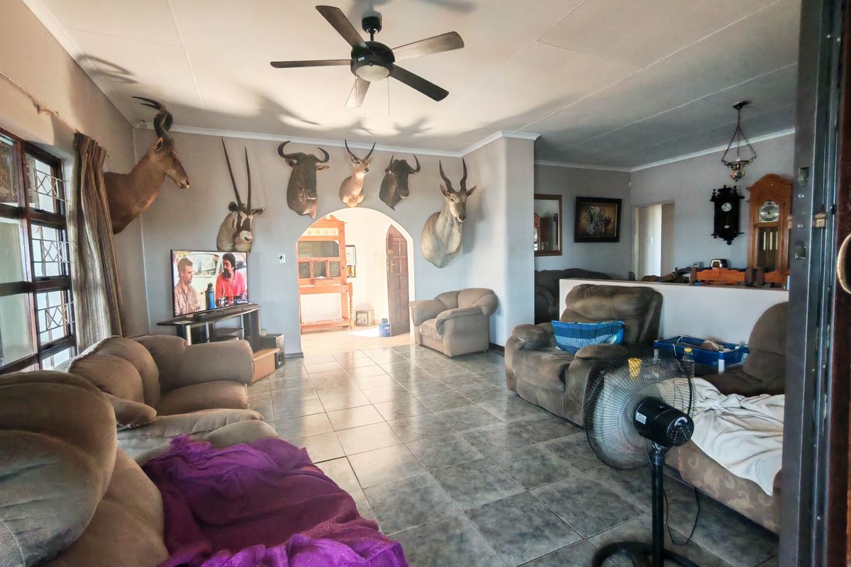 Spacious living room featuring tiled flooring, a ceiling fan, and an arched entryway leading to adjacent living areas.