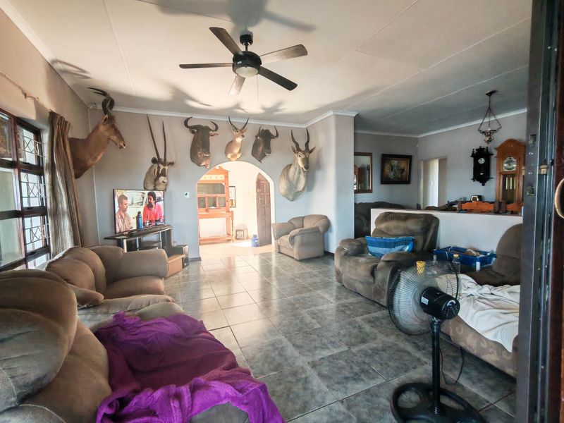 Spacious living room featuring tiled flooring, a ceiling fan, and an arched entryway leading to adjacent living areas.