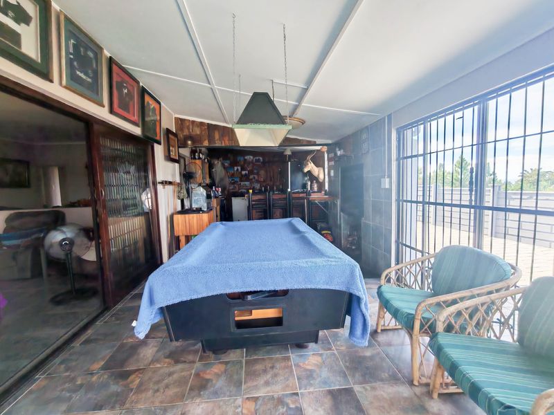 Enclosed patio area featuring tiled flooring, security bars, and a built-in bar counter, offering a versatile space for entertainment and relaxation.
