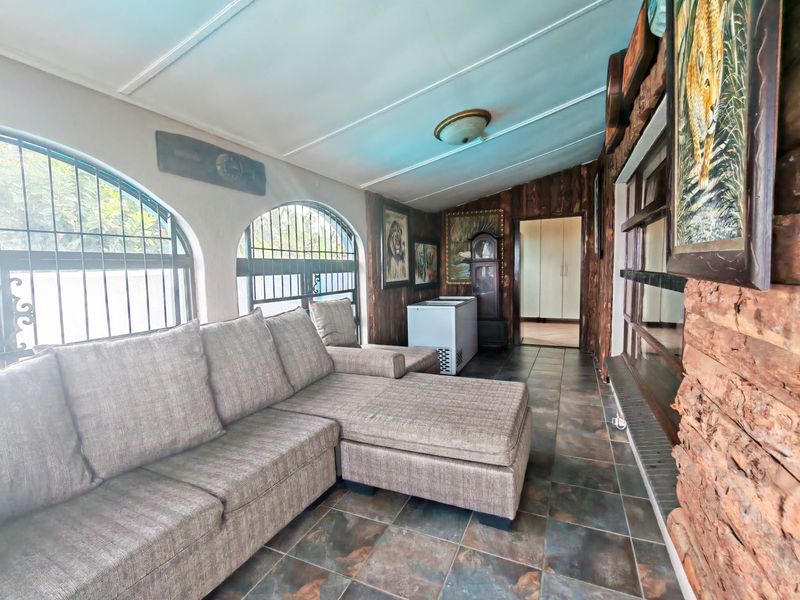 A living area featuring tiled flooring, wood-paneled walls, and arched windows with security bars, offering a rustic aesthetic.