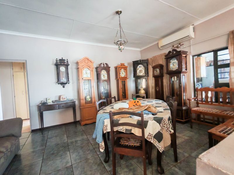 A dining room featuring tiled flooring, a split-system air conditioner, and a ceiling pendant light, offering a functional space for family meals.