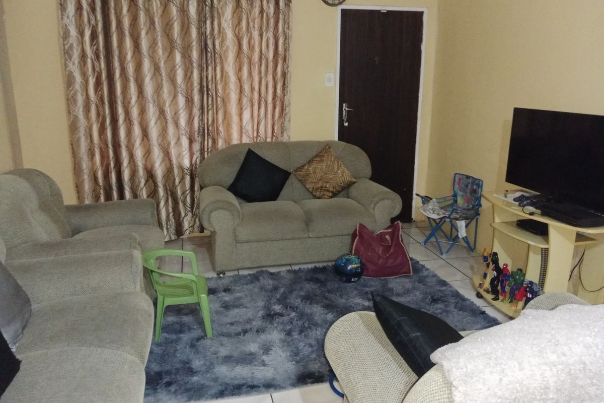 A standard living room area featuring tiled flooring and a solid core door, providing a functional space for relaxation.