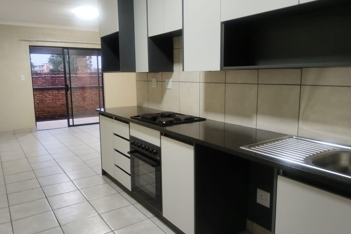 Modern kitchen featuring built-in cabinetry, electric hob, oven, and tiled finishes, leading directly to an outdoor patio area.