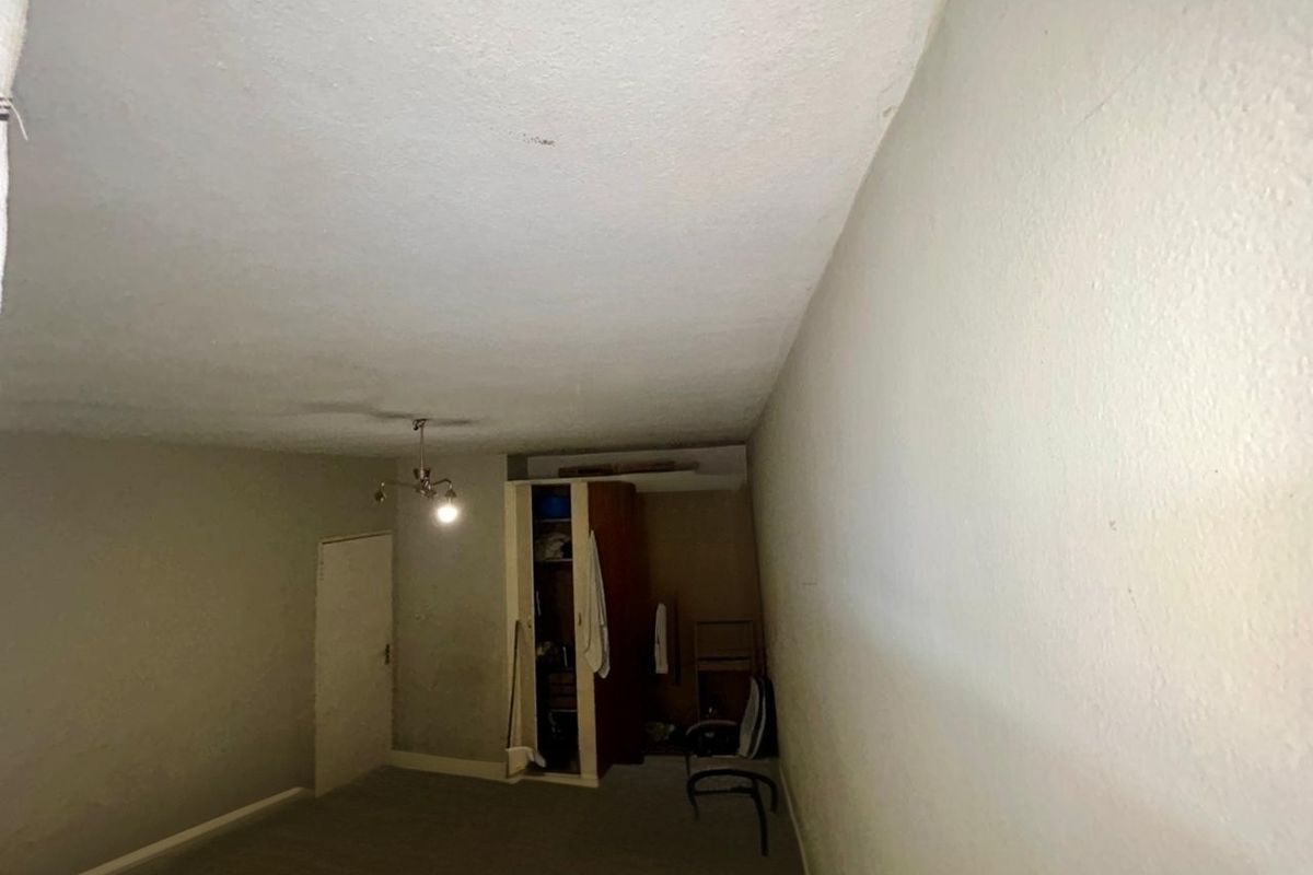 A bedroom featuring a built-in wardrobe and ceiling light fixture, requiring cosmetic updates to the walls and ceiling to improve its overall condition.