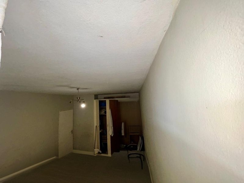 A bedroom featuring a built-in wardrobe and ceiling light fixture, requiring cosmetic updates to the walls and ceiling to improve its overall condition.