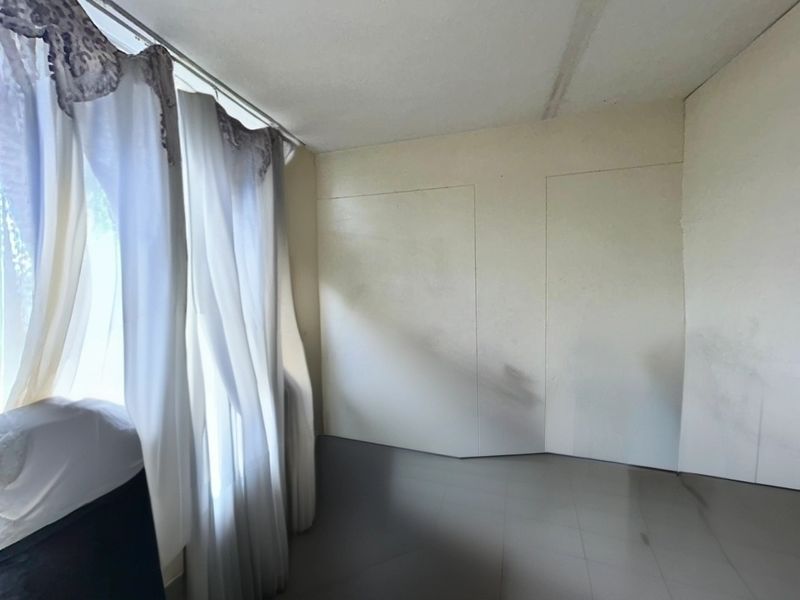 An empty bedroom featuring tiled flooring and wall panels, requiring cosmetic updates to address scuffing and surface wear.