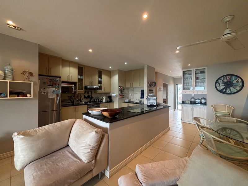 Spacious open-plan kitchen and dining area featuring granite countertops, ample built-in cabinetry, and tiled flooring, creating a functional and connected living space.