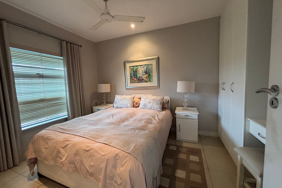 A well-maintained bedroom featuring built-in cupboards, tiled flooring, and a ceiling fan, offering a comfortable and functional living space.