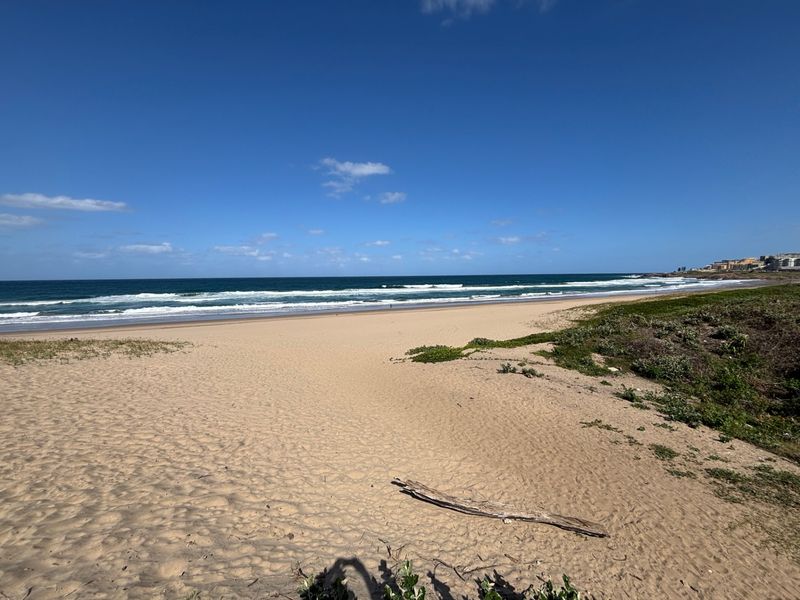 A scenic view of the sandy beach and ocean coastline, highlighting the property's proximity to the sea.