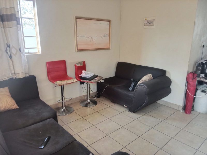 A living room area featuring tiled flooring and a wall-mounted electrical distribution board, offering a functional space ready for cosmetic updates.