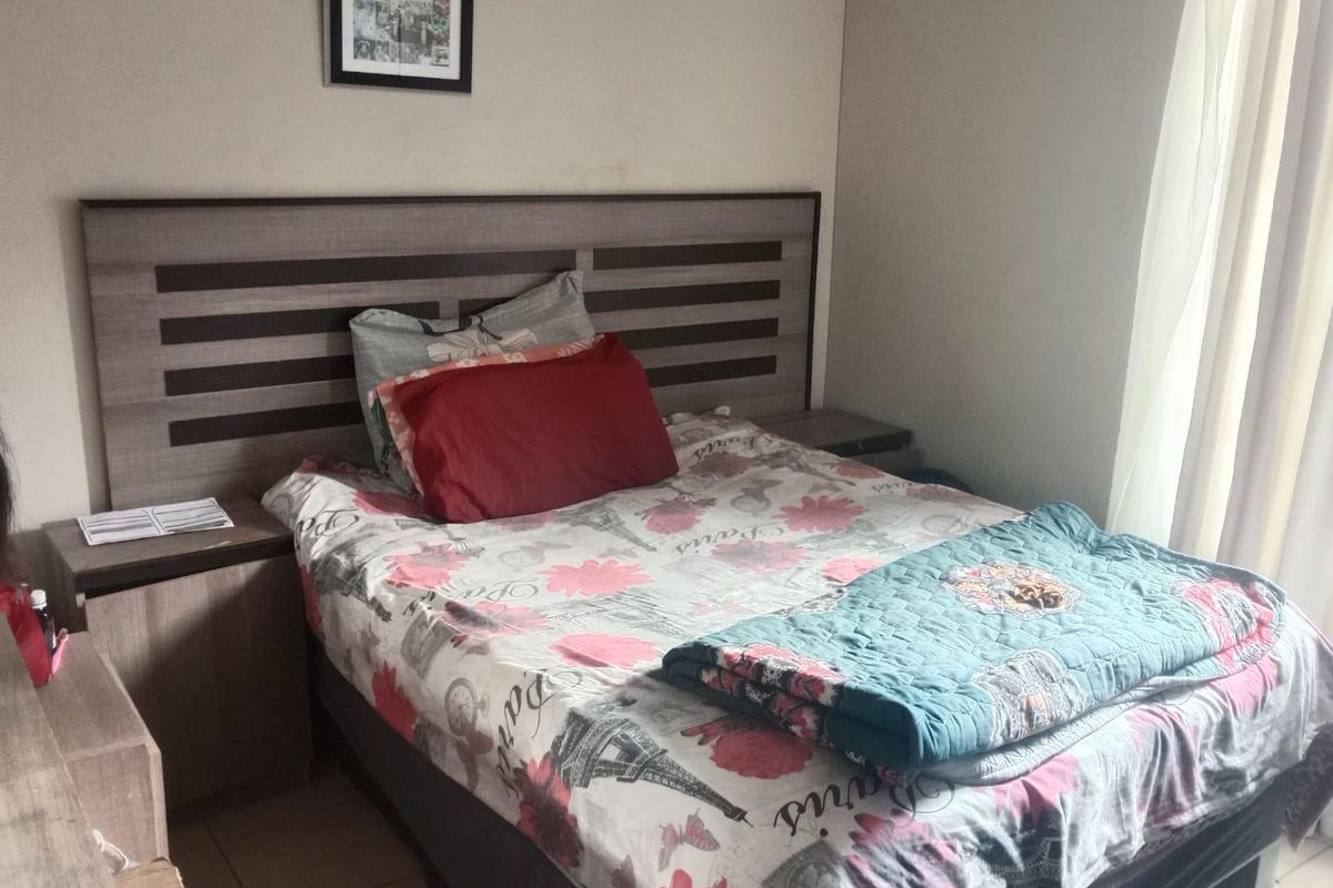 A bedroom featuring a built-in headboard with integrated bedside tables and tiled flooring, offering a functional layout with natural light.