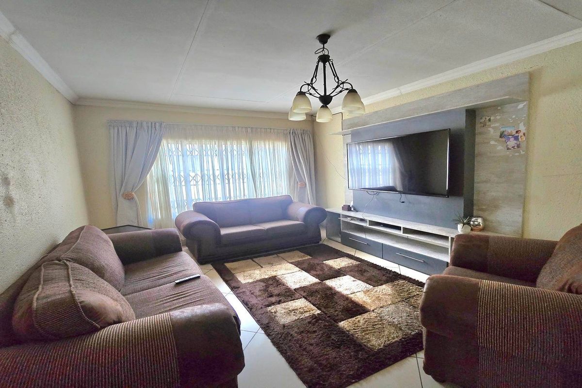 A comfortable living room featuring a built-in media wall, tiled flooring, and a central ceiling light fixture.