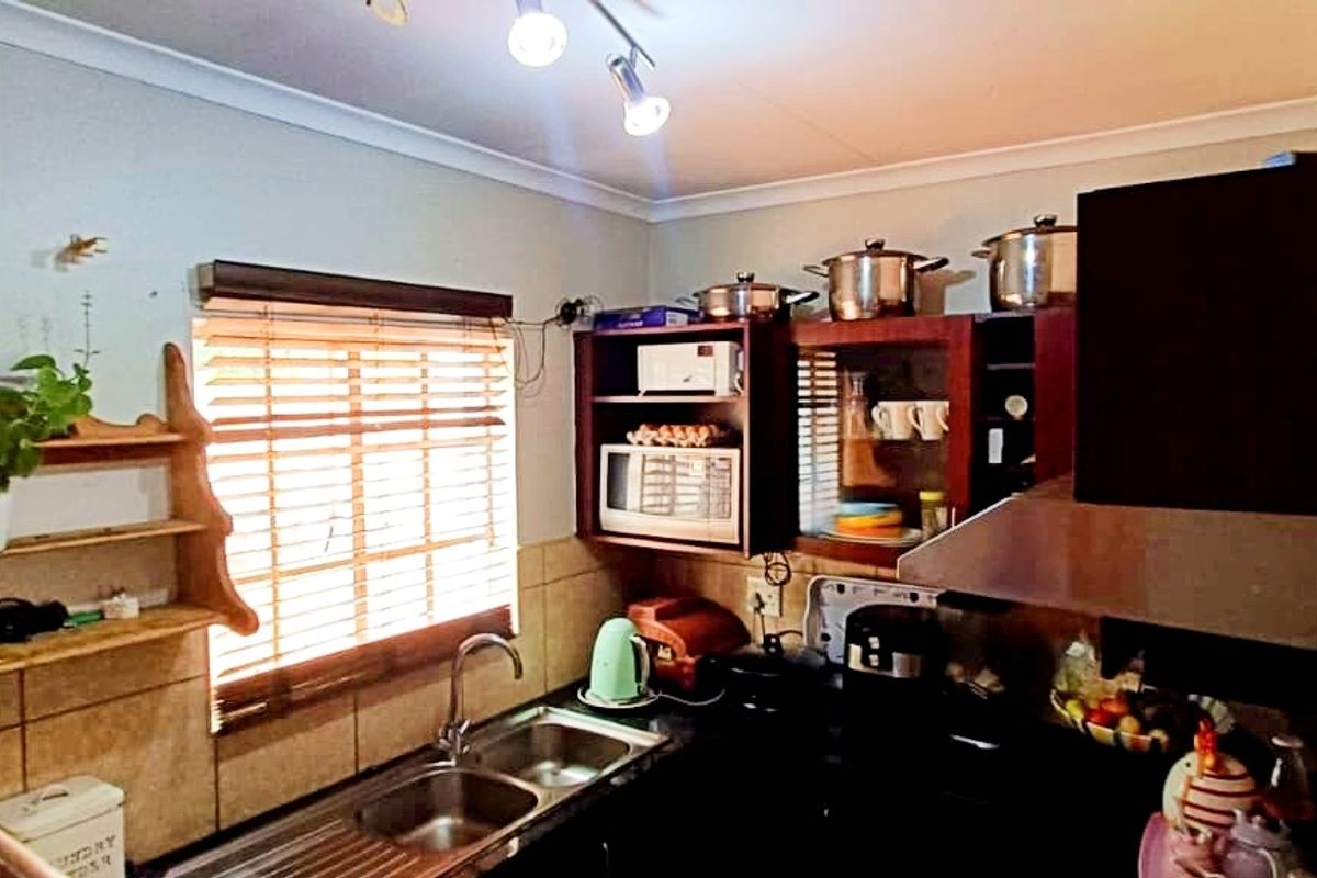 A functional kitchen featuring dark wood cabinetry, a double stainless steel sink, and a built-in extractor fan with tiled splashbacks.