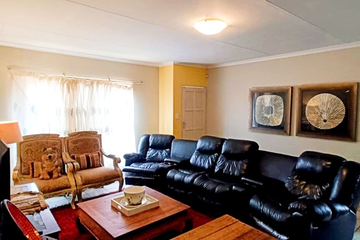 A living room featuring tiled flooring, a ceiling-mounted light fixture, and a doorway leading to an adjacent space.