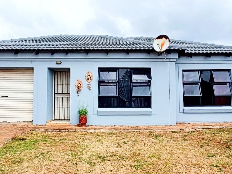 Front elevation of a single-story house featuring a tiled roof, roller garage door, security gate, and dark-framed windows.