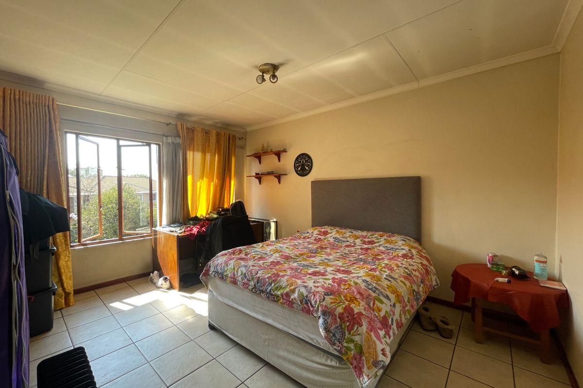 A spacious bedroom featuring tiled flooring and large casement windows that provide natural light.