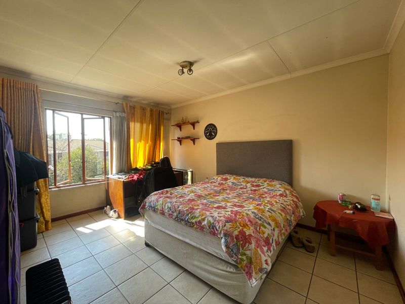 A spacious bedroom featuring tiled flooring and large casement windows that provide natural light.