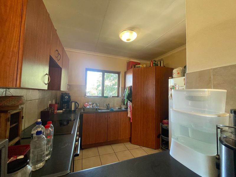A functional kitchen featuring laminate cabinetry, tiled backsplash, and ceramic flooring, offering a practical layout with potential for modern updates.