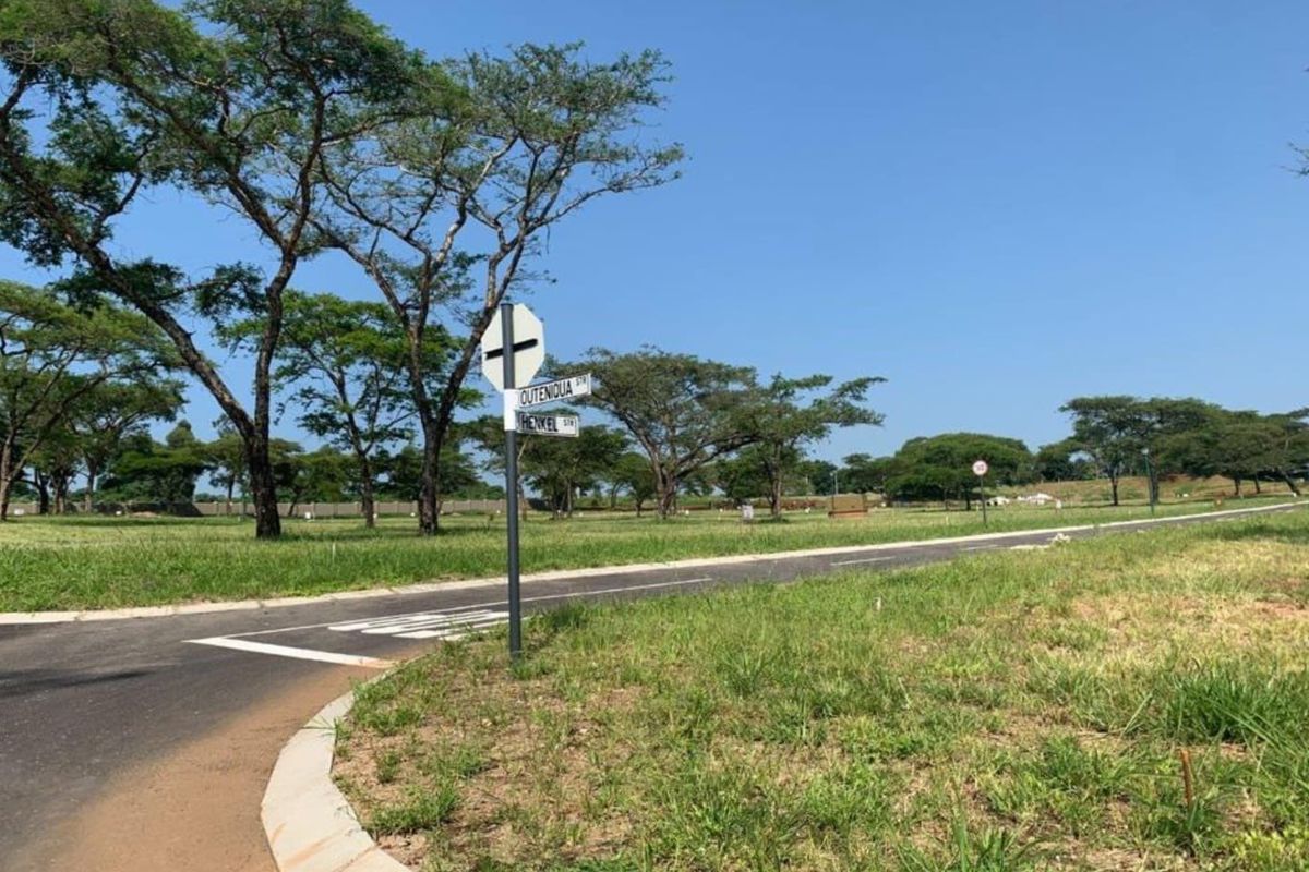 A view of a paved residential street corner with established trees and clear signage in a vacant land development.