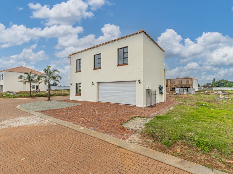 Front view of a modern double-story residential property featuring a double garage, paved driveway, and neutral exterior finish in a developing estate.