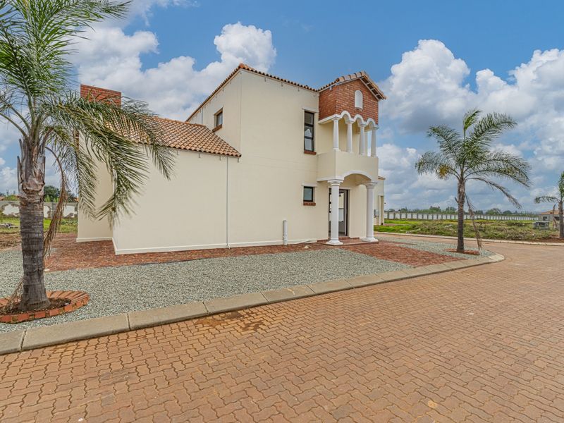 A well-maintained two-story residential property featuring a paved driveway, covered entrance with decorative columns, and a combination of plaster and brick exterior finishes.