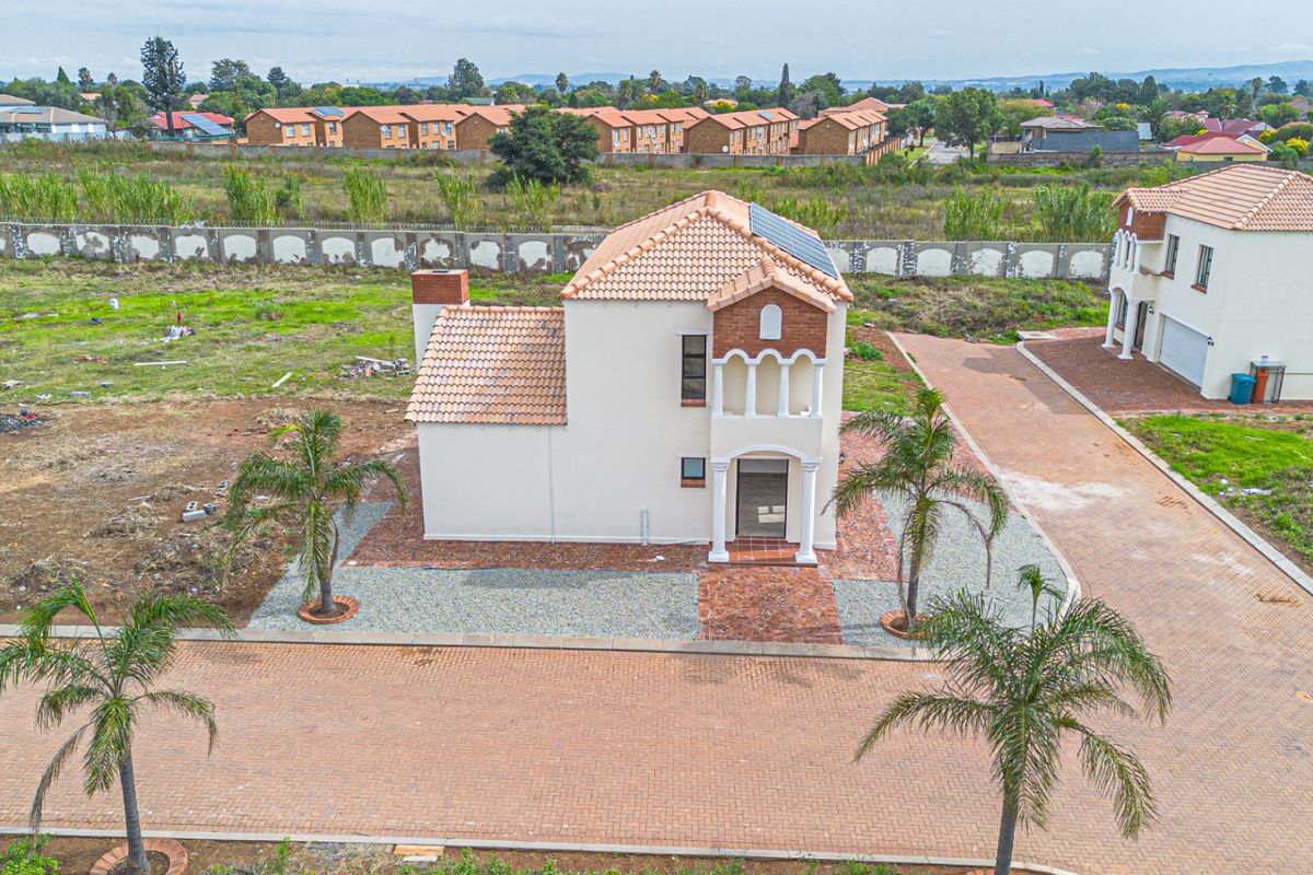 Aerial view of a detached two-story house featuring a terracotta tiled roof, solar panels, and a brick-paved driveway within a residential estate.