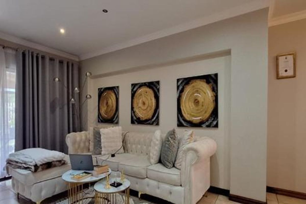 A well-maintained living room featuring tiled flooring, recessed downlighting, and a large sliding glass door providing access to the outdoor area.