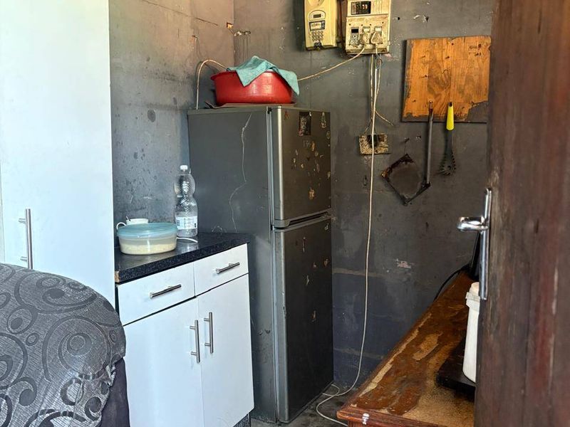 A small utility or storage space featuring exposed electrical infrastructure, unfinished walls, and basic built-in cabinetry with a laminate countertop.