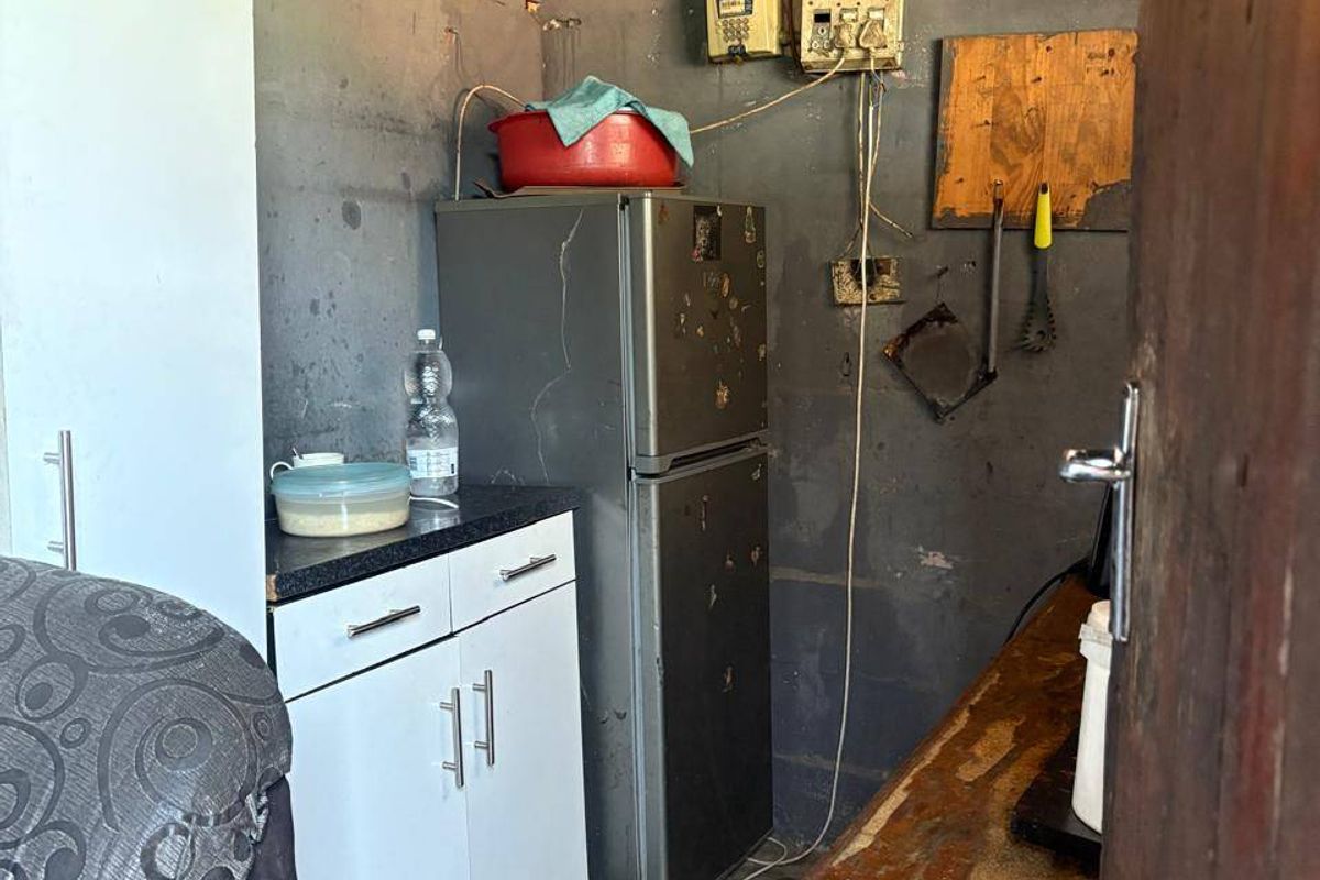 A small utility or storage space featuring exposed electrical infrastructure, unfinished walls, and basic built-in cabinetry with a laminate countertop.