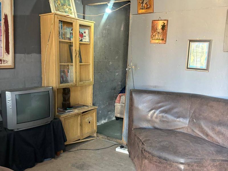 A living area featuring exposed roof structure and unfinished walls, requiring significant renovation to improve the overall condition and aesthetic appeal.
