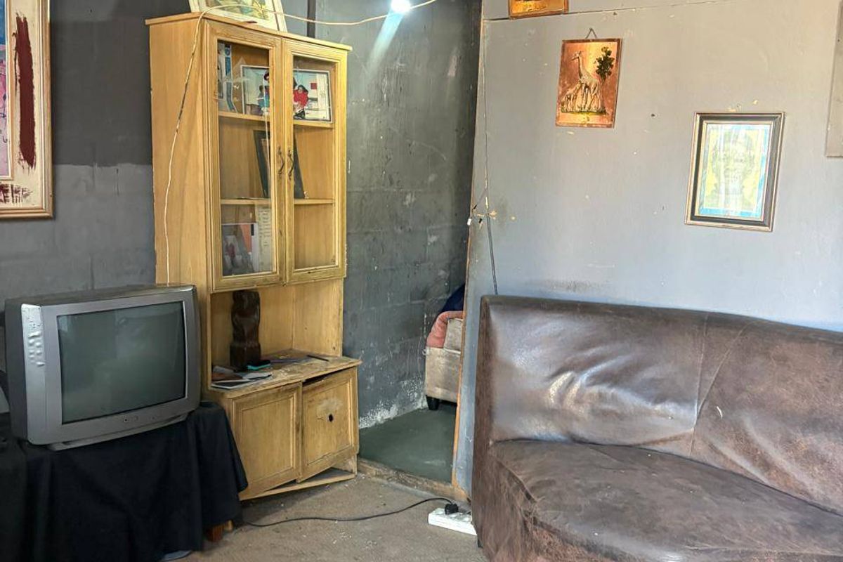 A living area featuring exposed roof structure and unfinished walls, requiring significant renovation to improve the overall condition and aesthetic appeal.