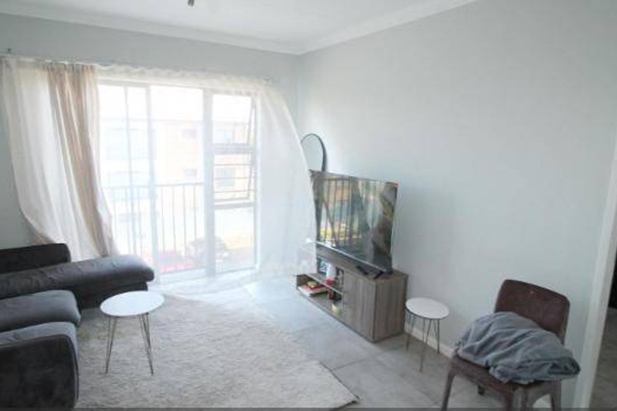 A living room featuring tiled flooring, coved ceilings, and a large sliding glass door providing access to an outdoor area.