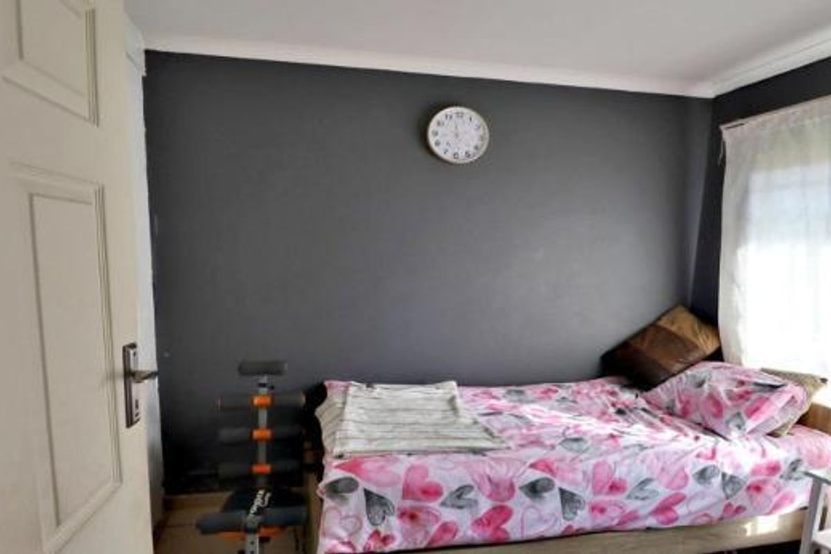 A bedroom featuring a dark accent wall, coving, and a panel door, providing a functional space for rest.