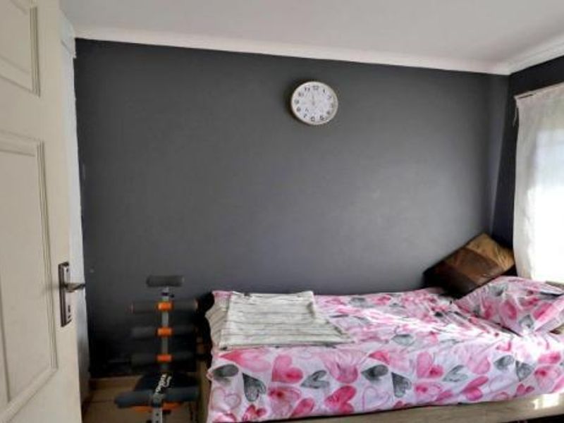 A bedroom featuring a dark accent wall, coving, and a panel door, providing a functional space for rest.