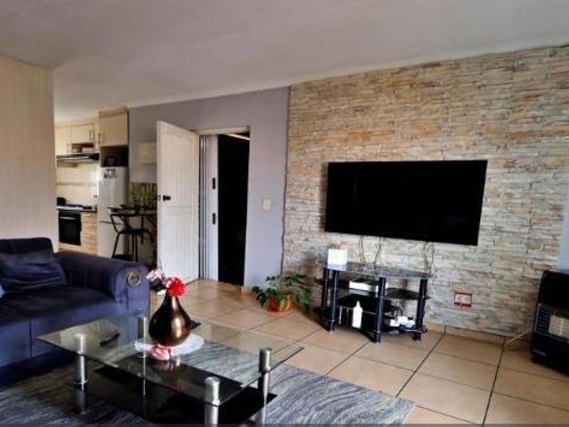 Open plan living area featuring a stone accent wall, tiled flooring, and direct access to the kitchen space.
