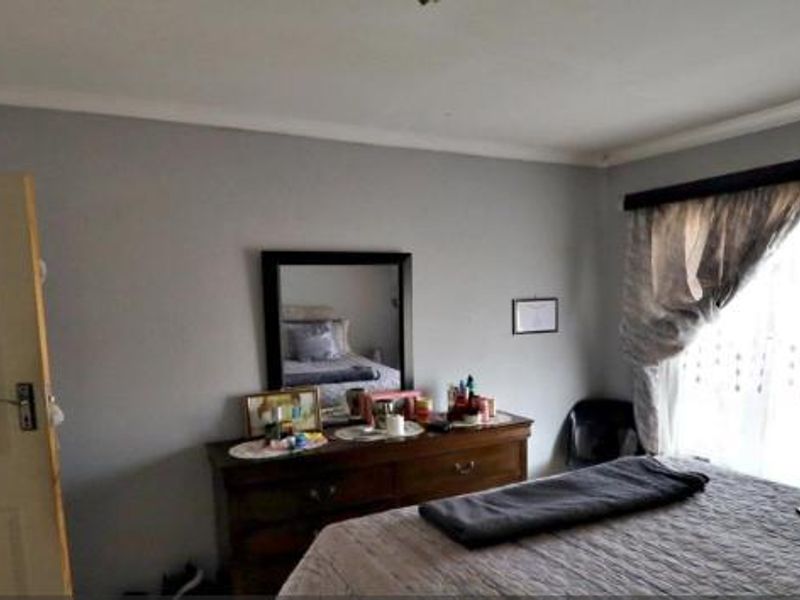 A standard bedroom featuring neutral wall finishes, a panel door, and window access with curtaining.