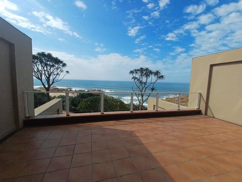 Spacious balcony featuring tiled flooring and a glass balustrade, offering expansive, unobstructed ocean views.