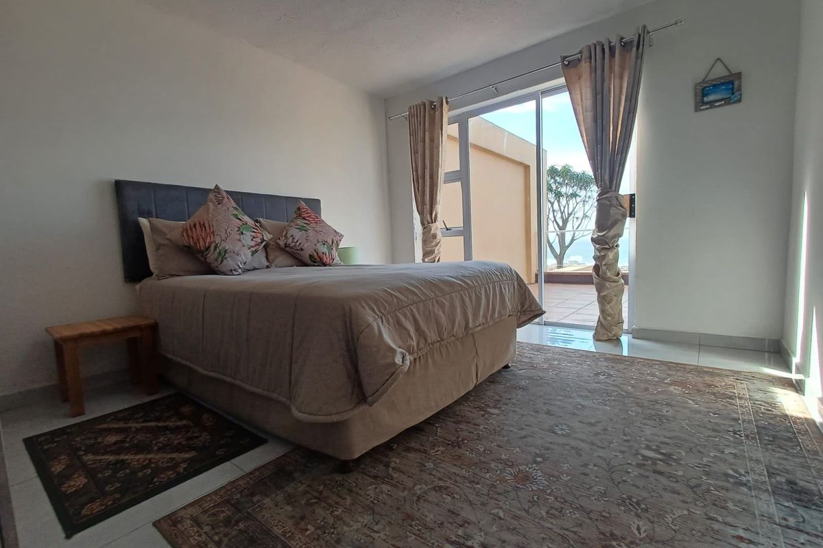 A bright bedroom featuring tiled flooring and a large sliding glass door that provides direct access to an outdoor balcony area.